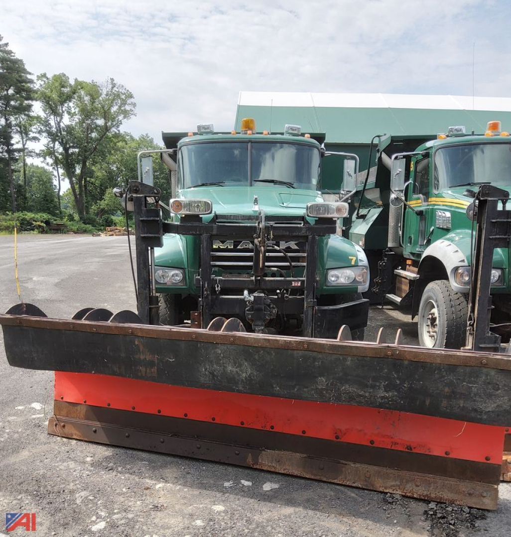 Mack Granite dump truck with plow attachment in front, green cab, two side-by-side trucks, plow blade featuring red stripe.
