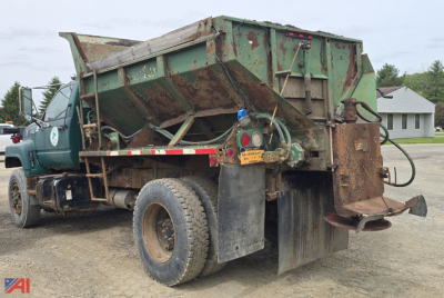 Dump truck bed in raised position on a 1996 GMC TopKick dump truck; visible rear hydraulic components, green cargo bed, mud flaps, and rear tires.