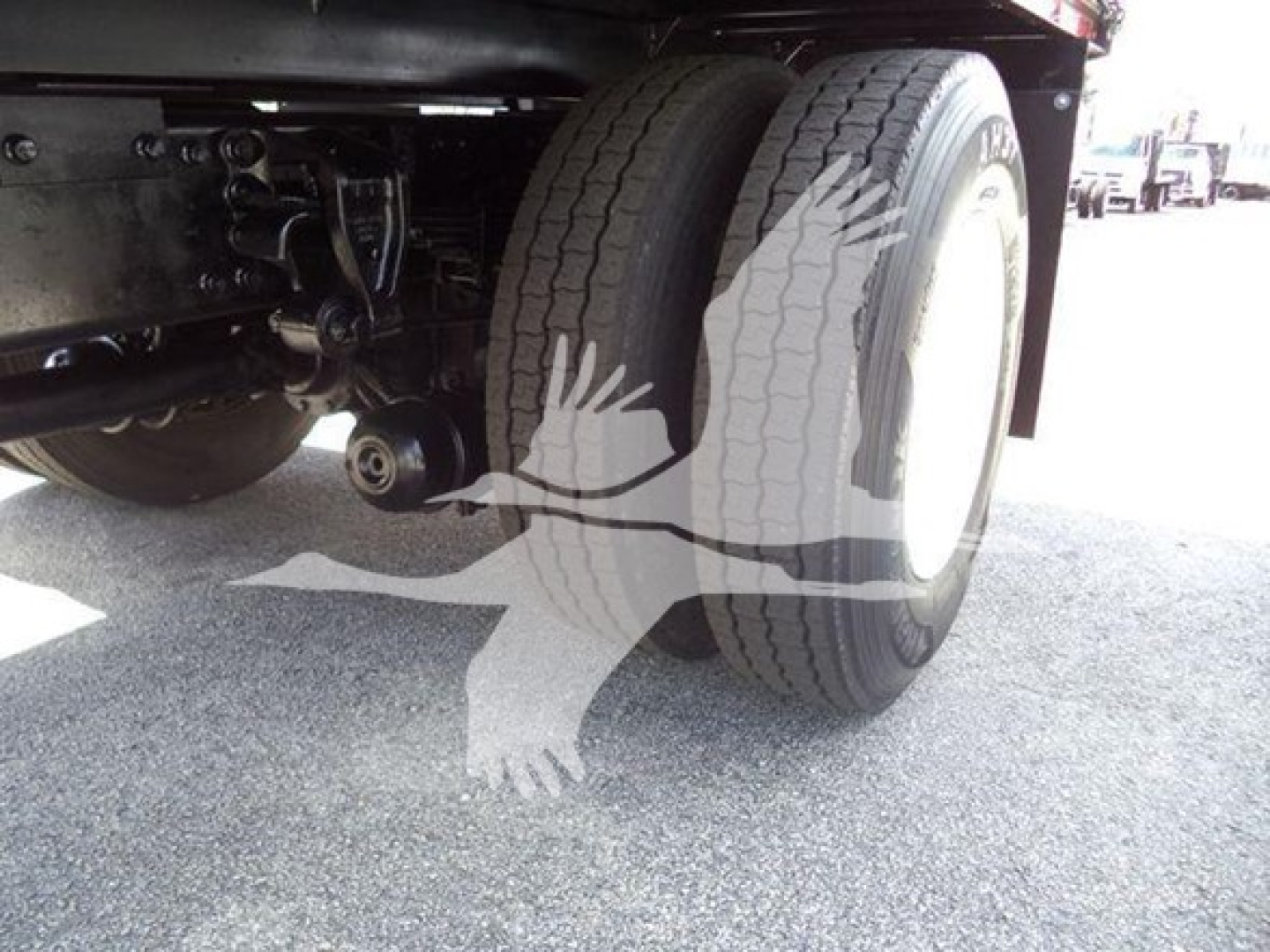 Truck axle and dual rear tires area of a 2016 Hino 268A dump truck showing twin wheels and suspension components.