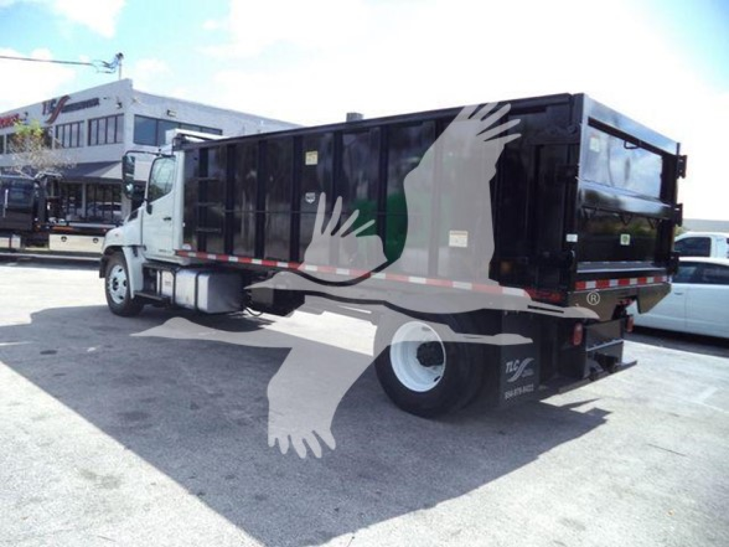 Used 2016 Hino 268A dump truck with a black dump body and white cab, side mirror, and wheels visible; VIN and stock text not visible in image.
