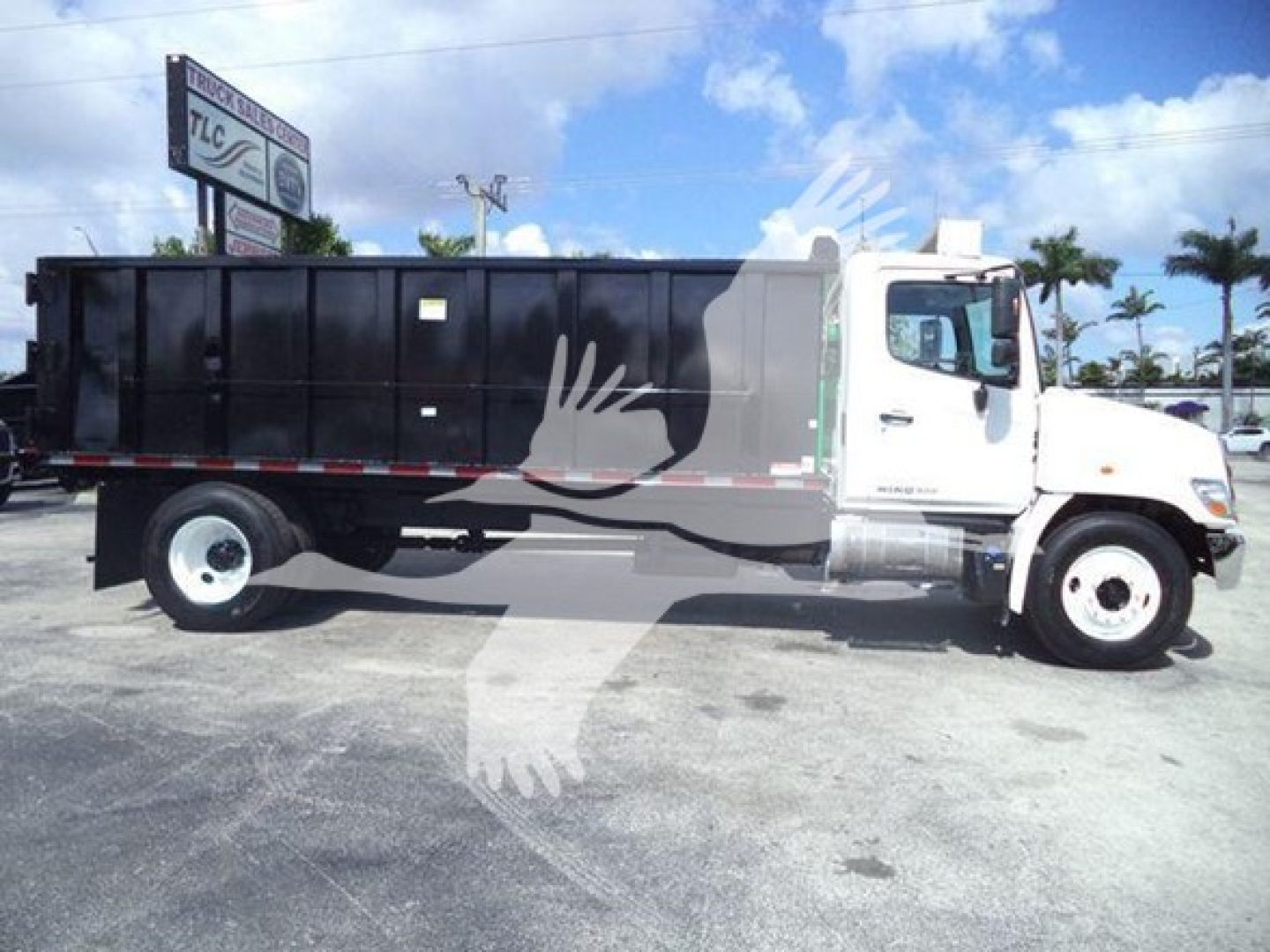 Truck side view of 2016 Hino 268A dump truck with black dump body and white cab, VIN 5PVNJ8JT6G4S57015 visible on listing, stock T57015.