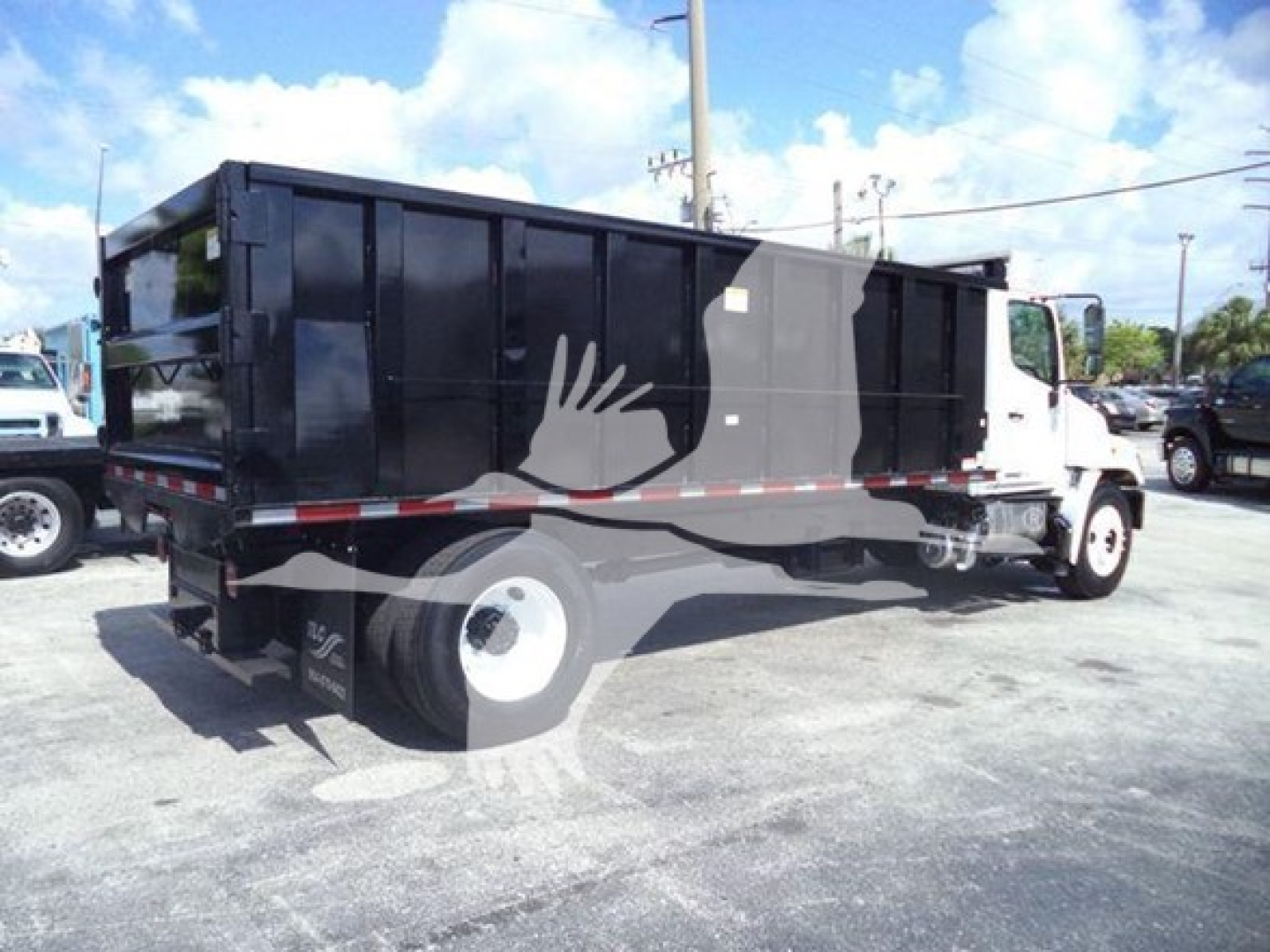 2016 Hino 268A dump truck side view showing dump body, white cab, black container, rear bumper, and stock lot environment.
