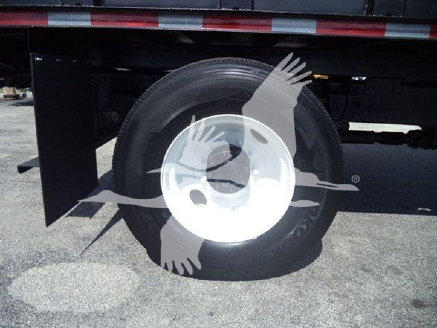 Rear wheel and undercarriage of a 2016 Hino 268A dump truck showing wheel and tire with reflective side panel.