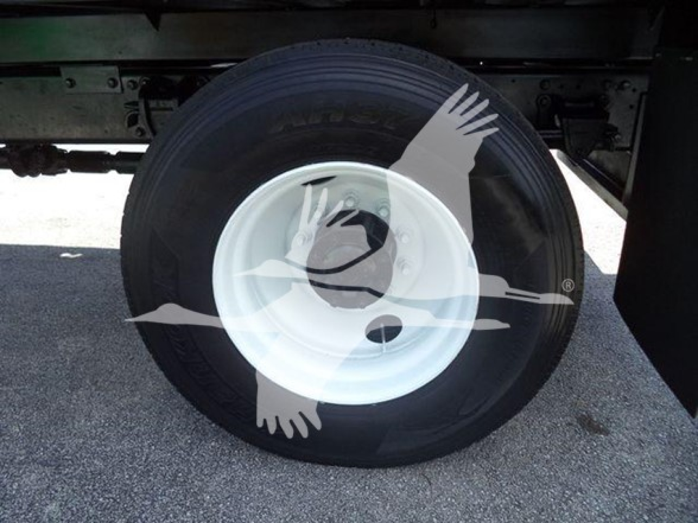Wheel with white rim and tire under truck chassis; no legible labels or text visible on components.