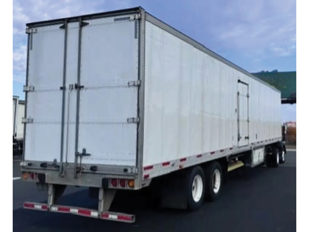 Utility 3000R trailer side/rear view showing dual rear doors and white exterior with safety reflectors along lower edge.