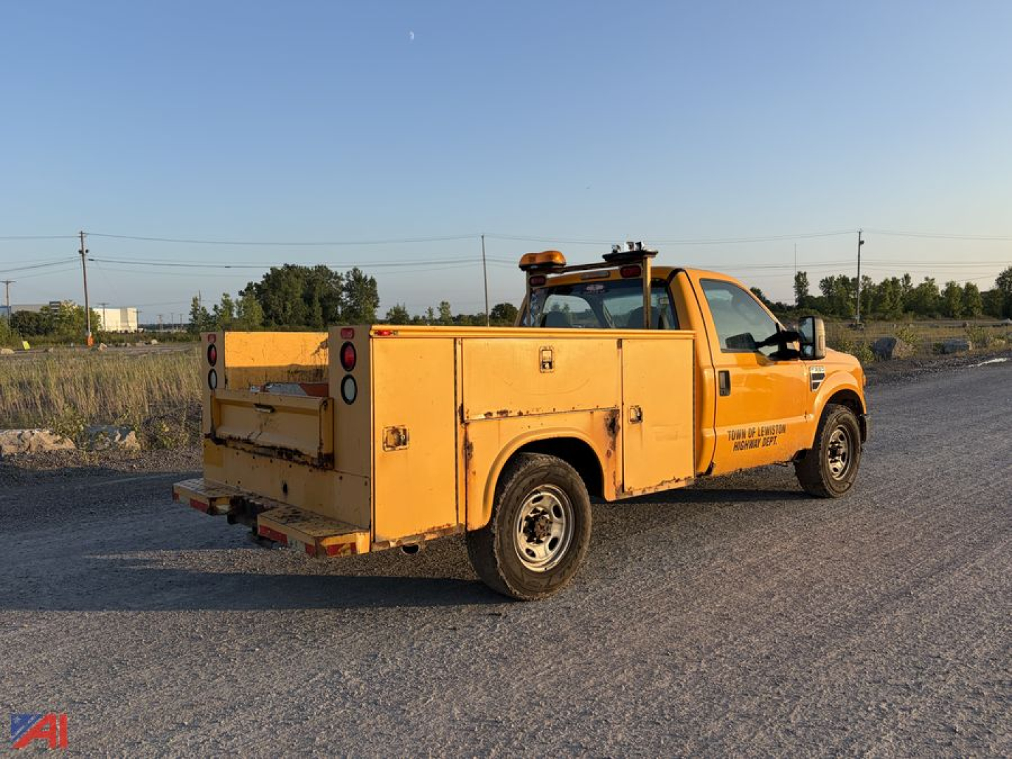 Ford F-350 Super Duty utility truck in service yellow with utility bed and amber warning light on cab roof, rear cargo area doors