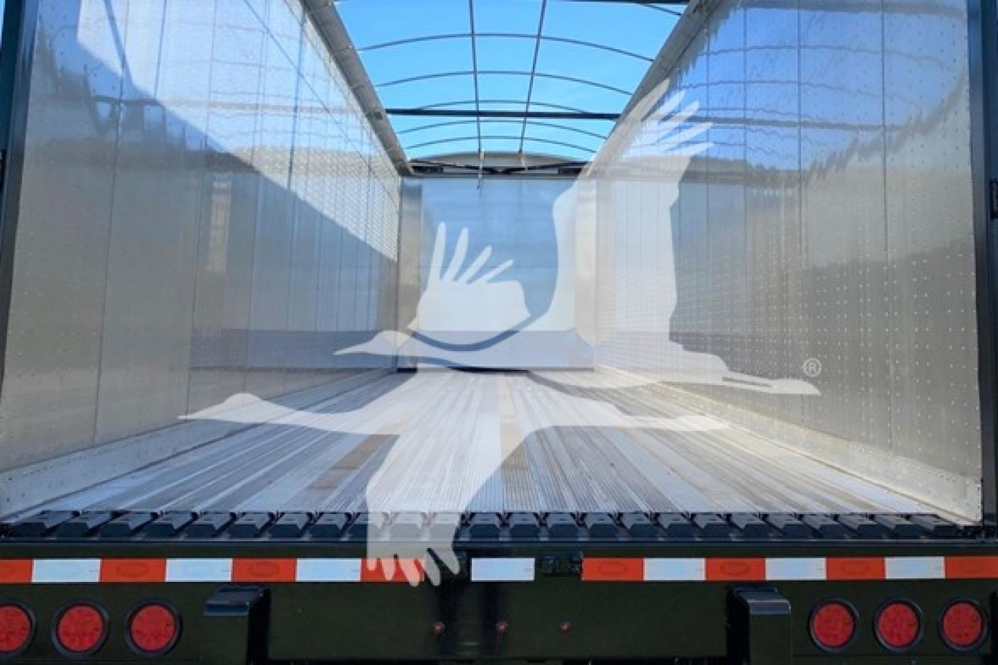 Trailer interior view showing a Dorsey walking floor trailer with enclosed steel side walls and wooden floor, rear with taillights and reflective tape.
