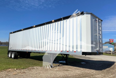 Dorsey walking floor trailer in an outdoor lot showing side and rear of silver corrugated trailer with support legs down.