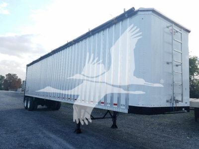 Trailering equipment showing a long silver Dorsey walking floor trailer with a large white bird graphic on the side, rear ladder, and support legs.