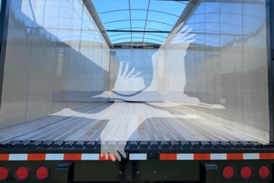 Trailer interior view showing a Dorsey walking floor trailer with enclosed steel side walls and wooden floor, rear with taillights and reflective tape.