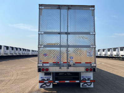 Truck trailer rear view with diamond plate metal doors, red and white reflective safety stripes, and multiple trailer brands on the bumper area.