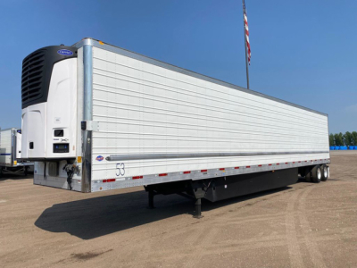Trailer refrigerated dry van with Carrier refrigeration unit showing serial tag and axles; white exterior with reflective tape.
