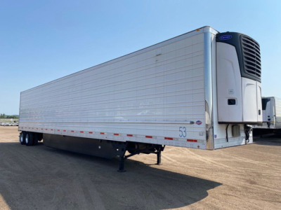 Trailer side view of a 2021 Utility reefer trailer with a blue Ford refrigeration unit, silver aluminum panels, and landing gear visible.