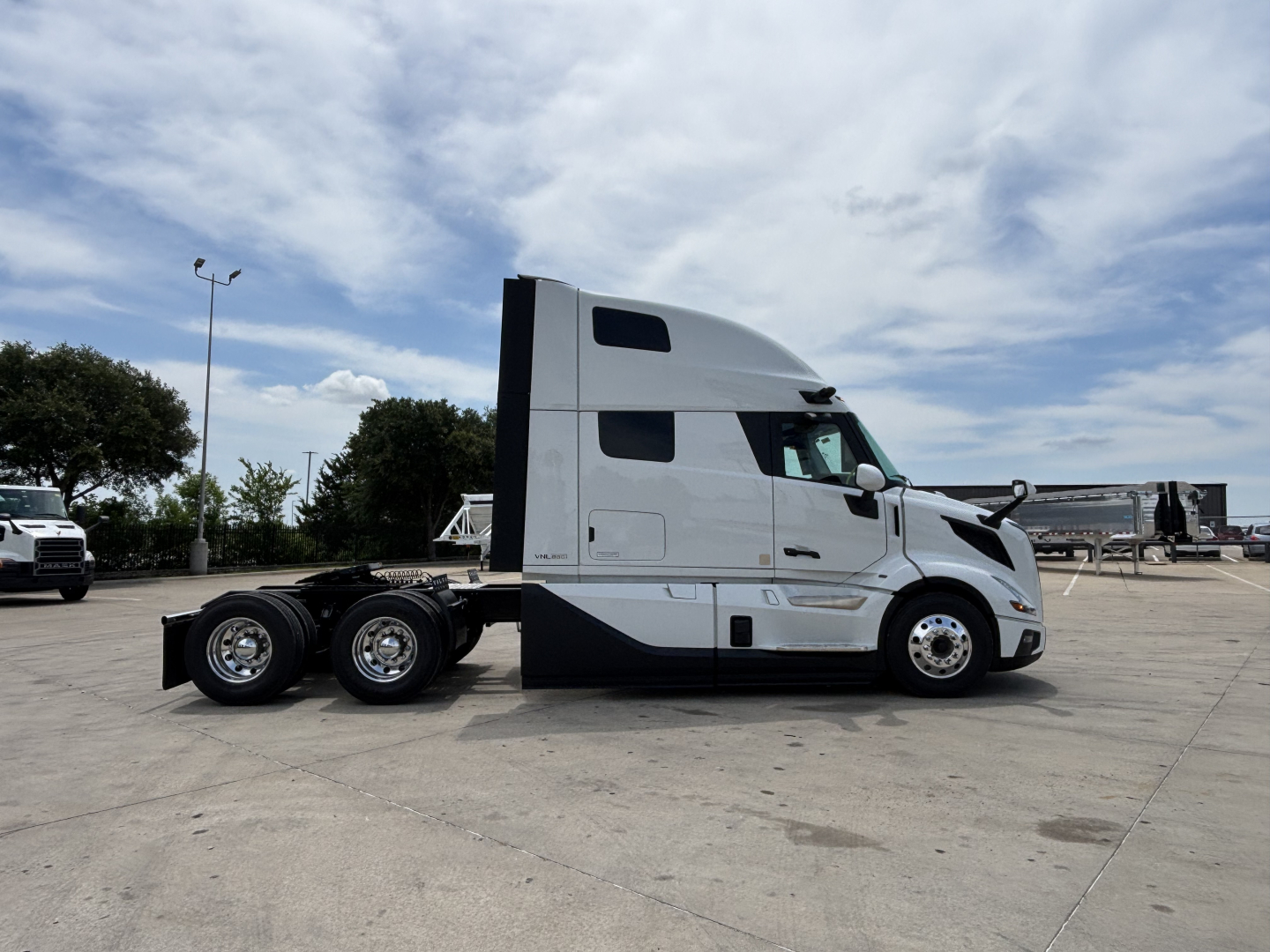 Semi truck side view showing sleeper cab with Volvo branding and chrome wheels; no visible text on side besides the window shapes.