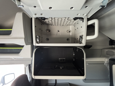 Volvo VNL64T860 cab interior showing open overhead storage compartment and lower storage drawer.