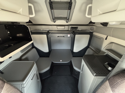 Volvo VNL64T860 cabin interior showing sleeper area with table and seating, light gray cabinetry, and controls.