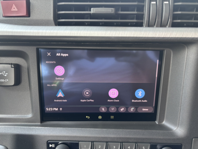 In-vehicle infotainment touchscreen displaying Android Auto and Apps menu in Volvo VNL cabin, with surrounding dashboard vents and hazard button.