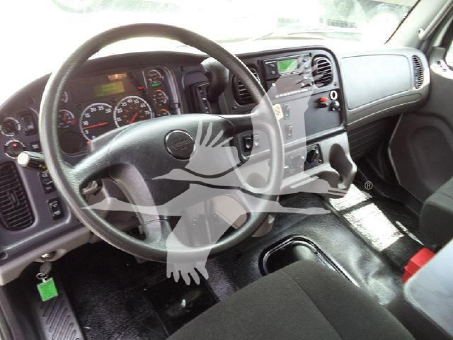 Freightliner M2 106 cab interior showing steering wheel, dashboard gauges, center console, and gear shifter.