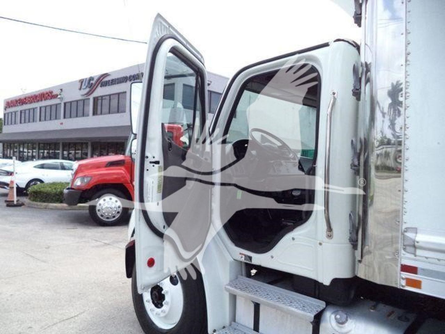 Truck cab interior open doors showing entry steps and steering wheel in a Freightliner M2 106 box truck.