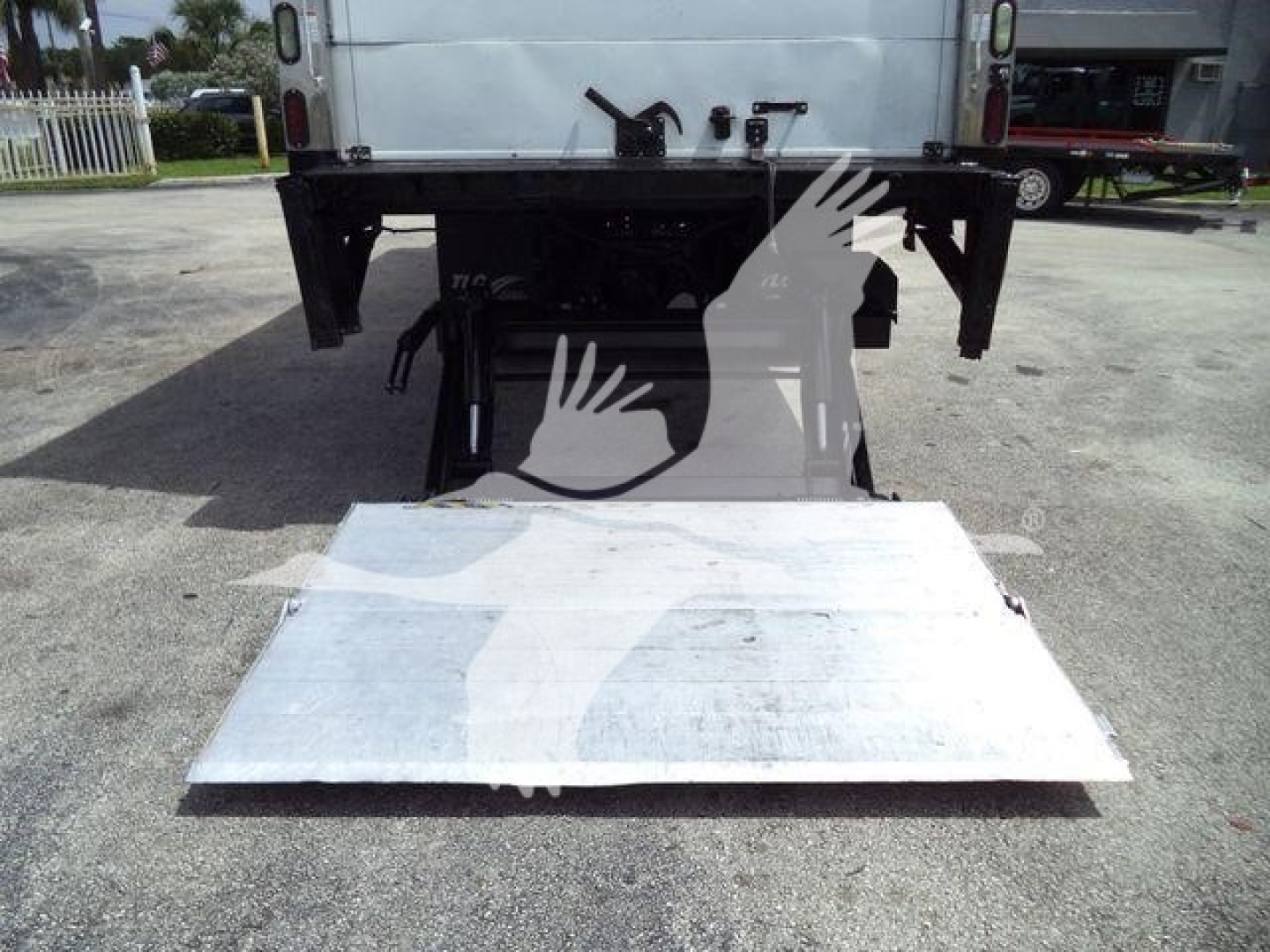 Truck bed with liftgate in raised position showing metal platform and rear chassis of a Freightliner M2 106.