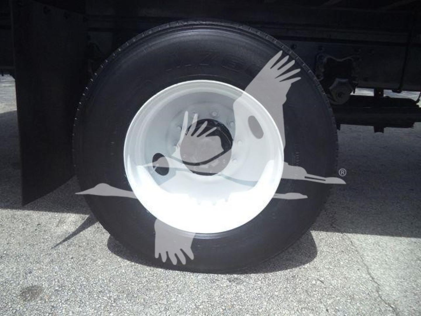 Truck wheel showing spare wheel with white steel rim and black tire on Freightliner M2 106 undercarriage.
