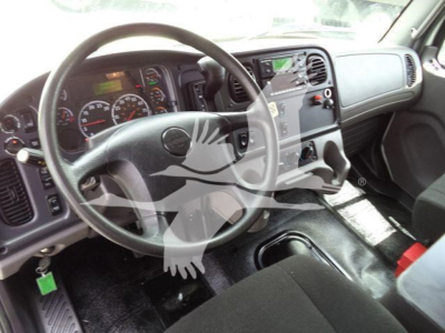 Freightliner M2 106 cab interior showing steering wheel, dashboard gauges, center console, and gear shifter.