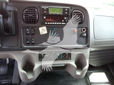 Dashboard of 2023 Freightliner M2 106 interior showing radio, climate controls, cup holders, and storage compartments.