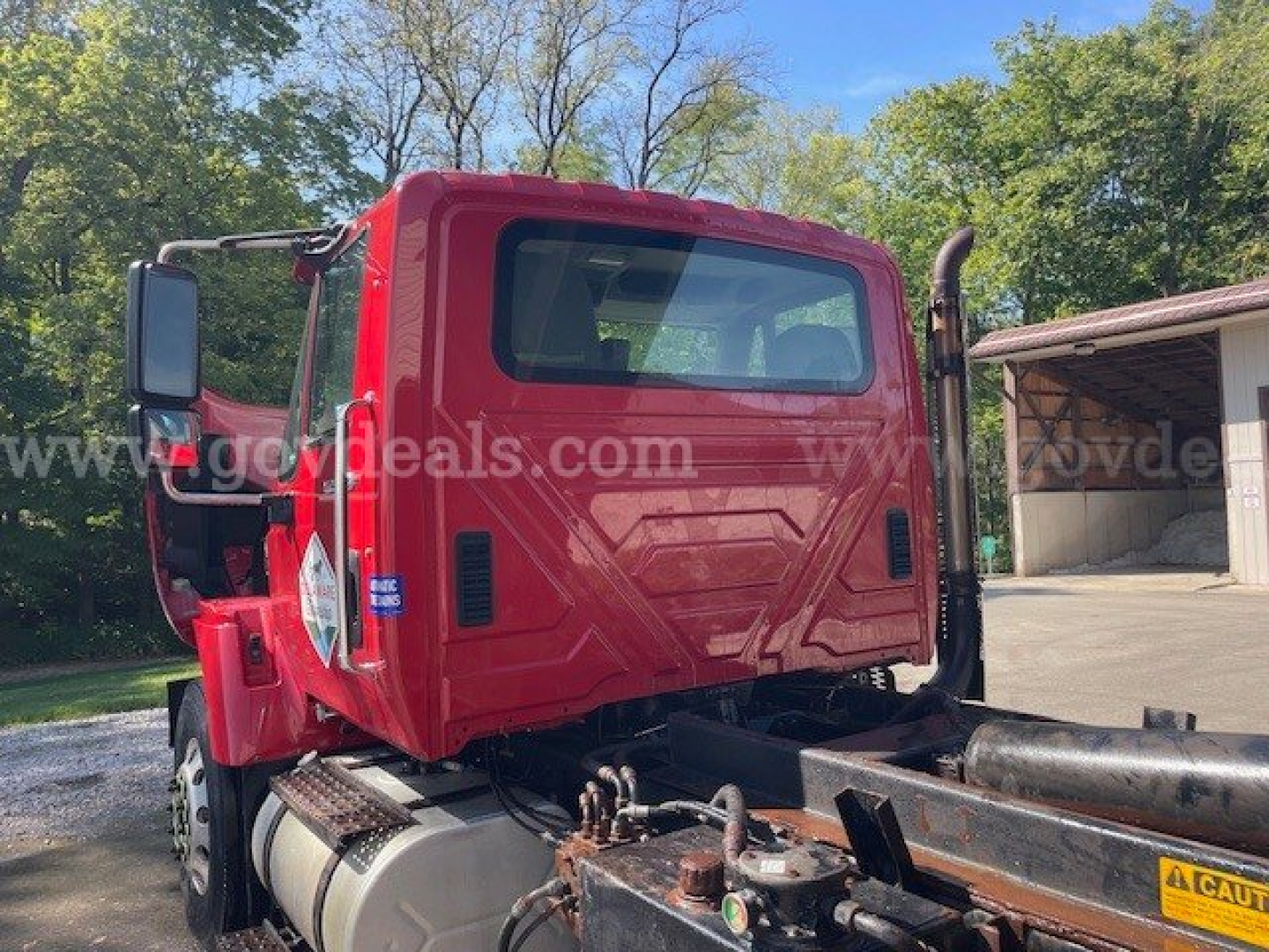 Truck cab rear and chassis of a red 2010 International Maxxforce DT 7400 plow truck showing rear cab windows, fuel tank, and frame.