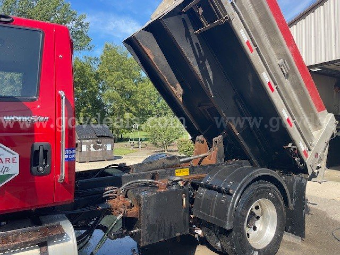 Truck chassis with raised dump bed showing hydraulic components and rear wheel area