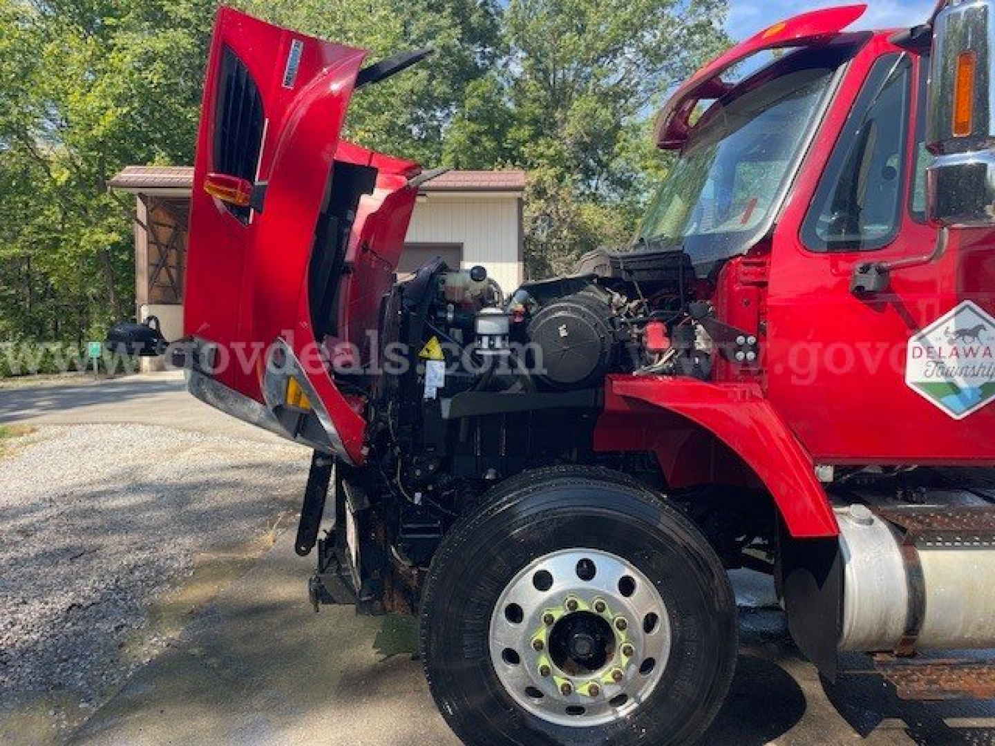 Truck engine bay of a red 2010 International Maxxforce DT plow truck in-service, side hood open showing engine components.