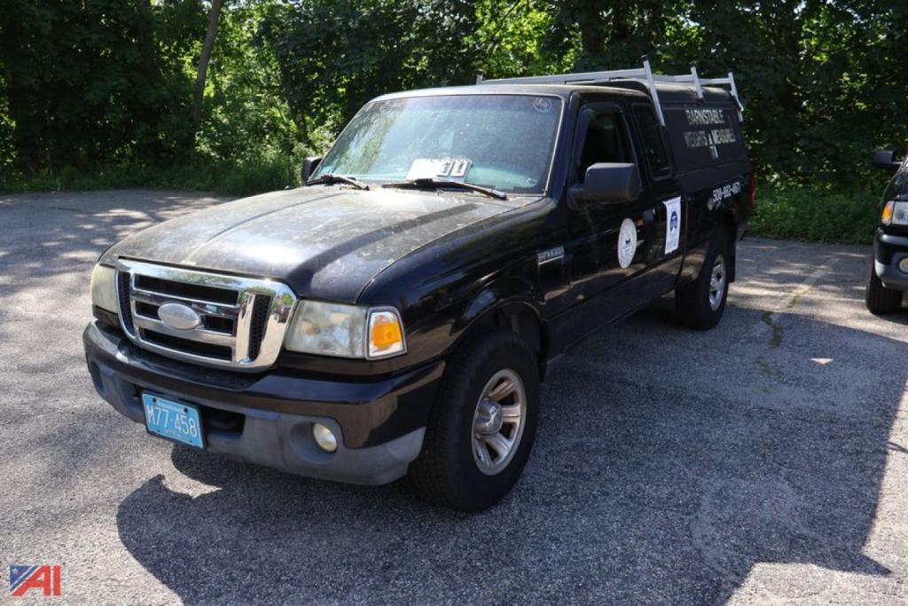 Ford Ranger pickup truck in a parking lot, black extended cab, front view, with running boards and ladder rack on roof, Ohio plates.