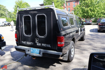 Ford Ranger pickup with black camper shell rear view showing dual rear doors and rear bumper text.