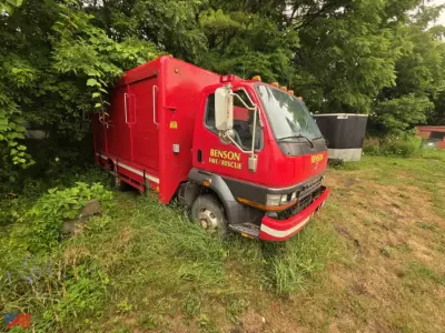 Red Mitsubishi Fuso FH211 rescue truck with multiple compartment doors and Benson Fire/Rescue labeling, front bumper guard, parked on grass.