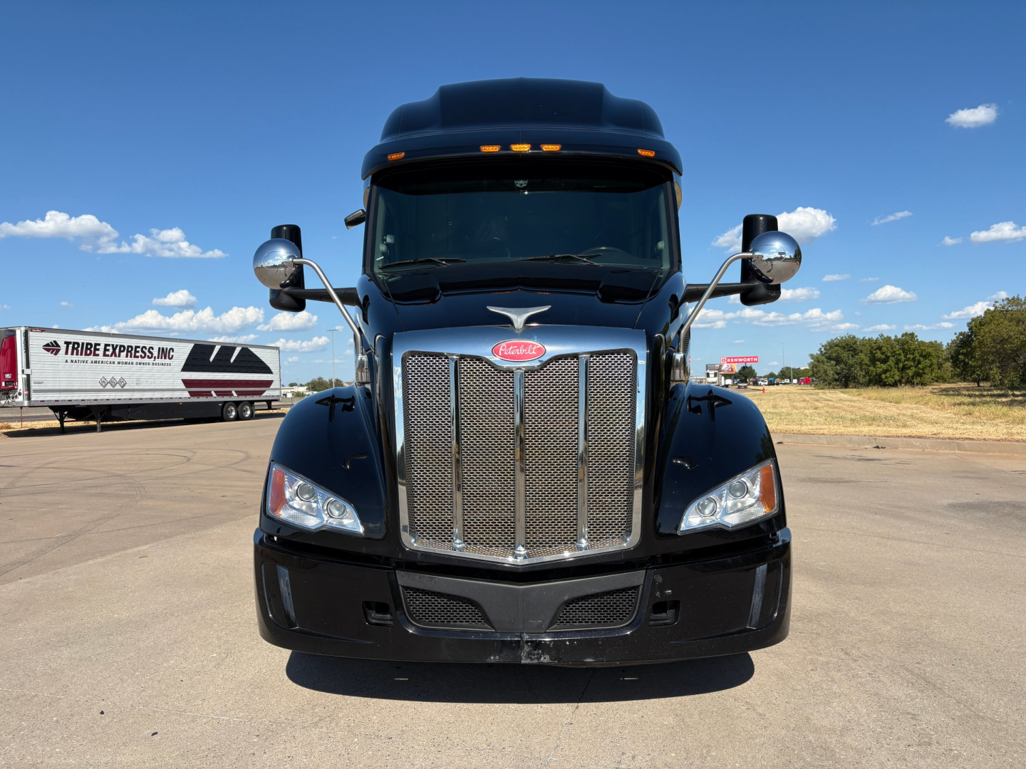 Peterbilt 579 truck front view showing chrome grille, headlights, and emblem in a parking lot.