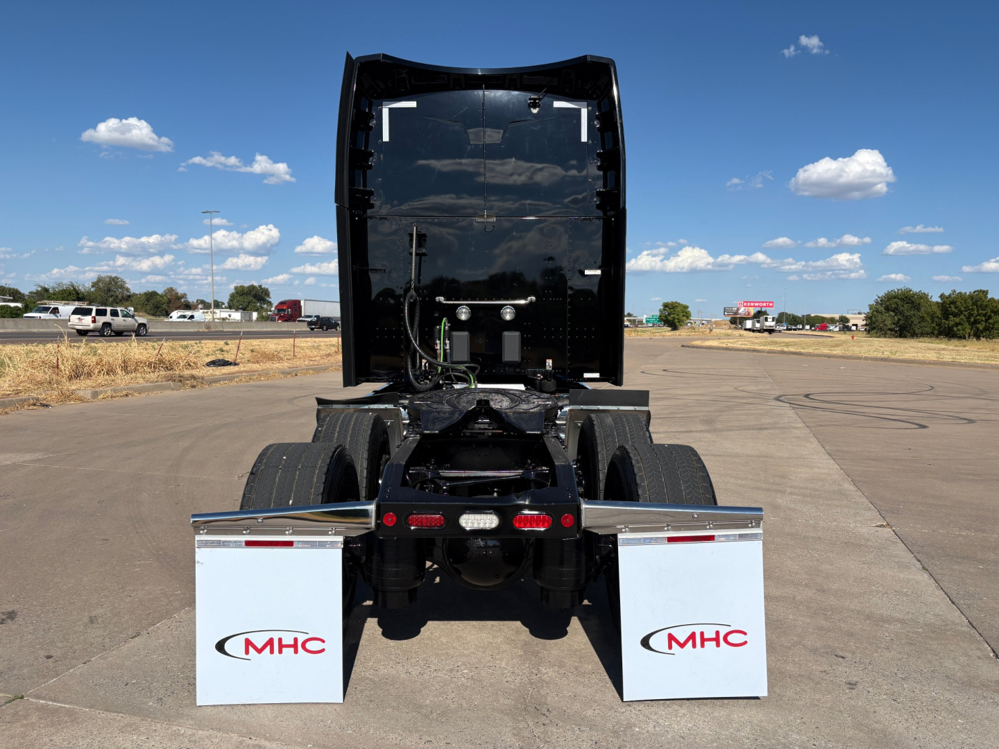 Peterbilt 579 rear view showing fifth wheel and mudflaps with MHC logo.
