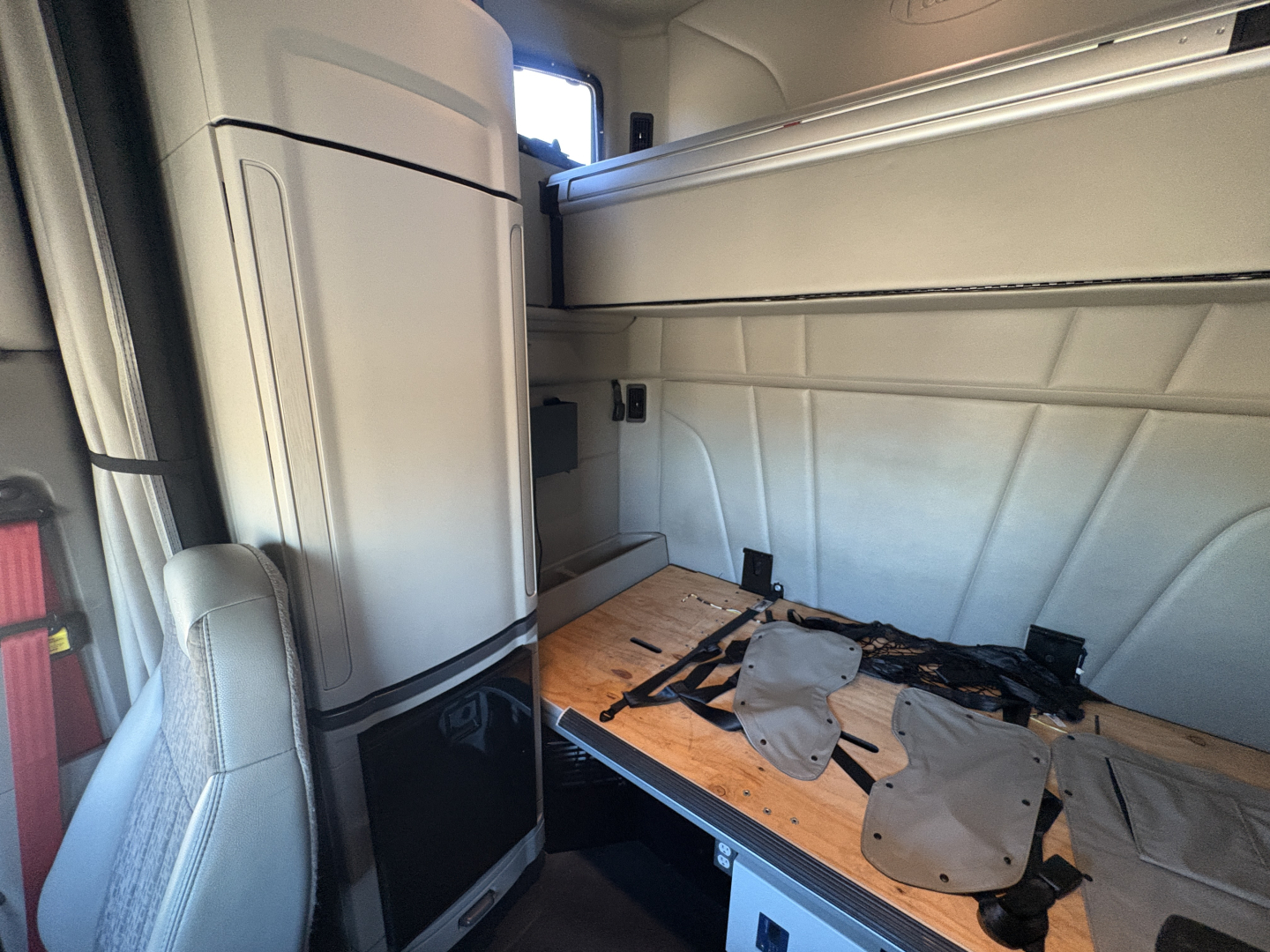 Peterbilt 579 truck cab interior showing sleeper area and storage compartments with a wooden floor panel and seat in view.
