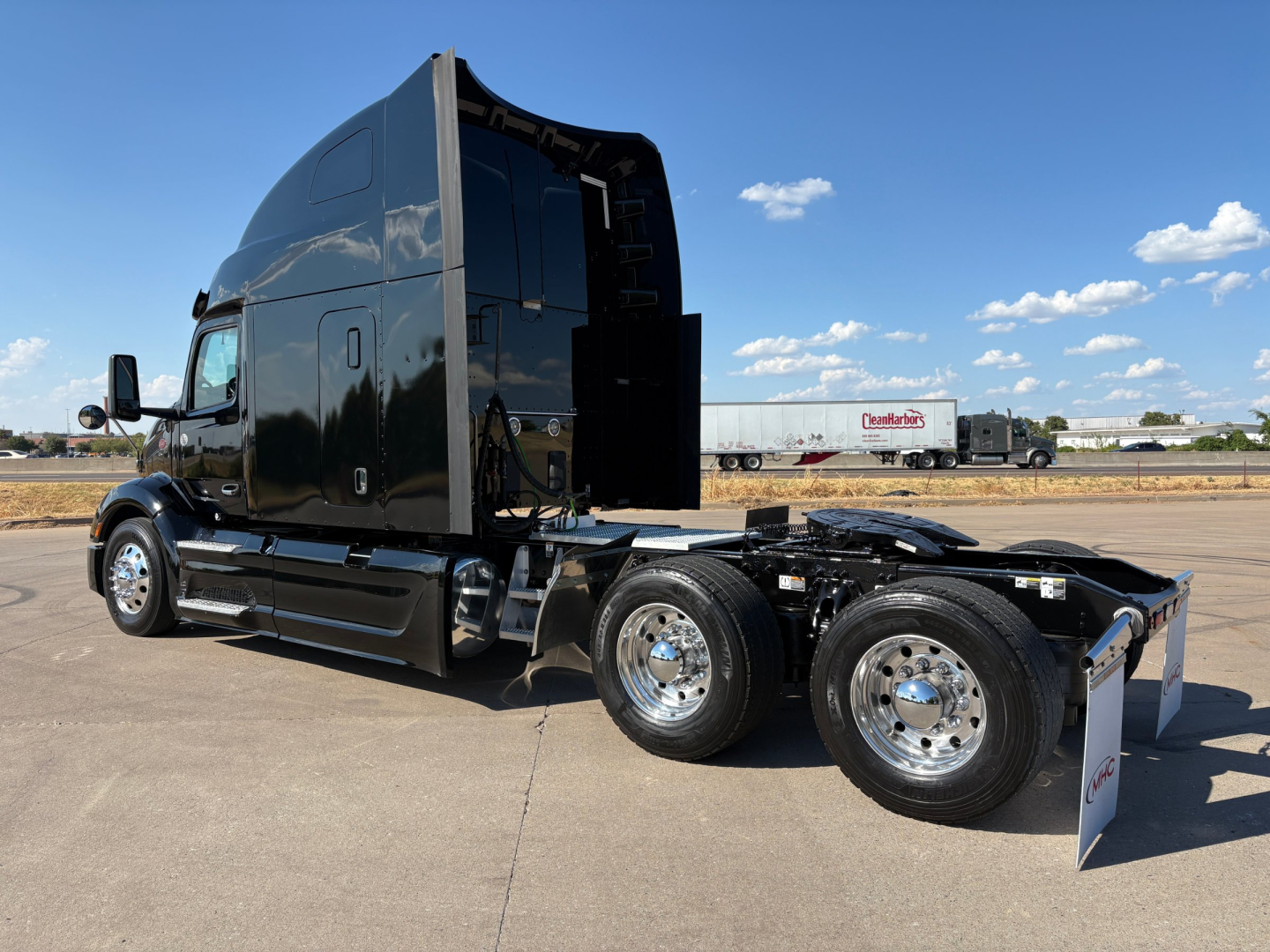 Peterbilt 579 tractor with sleeper, black paint, displaying dual rear axles, cab high roof, chrome wheels.