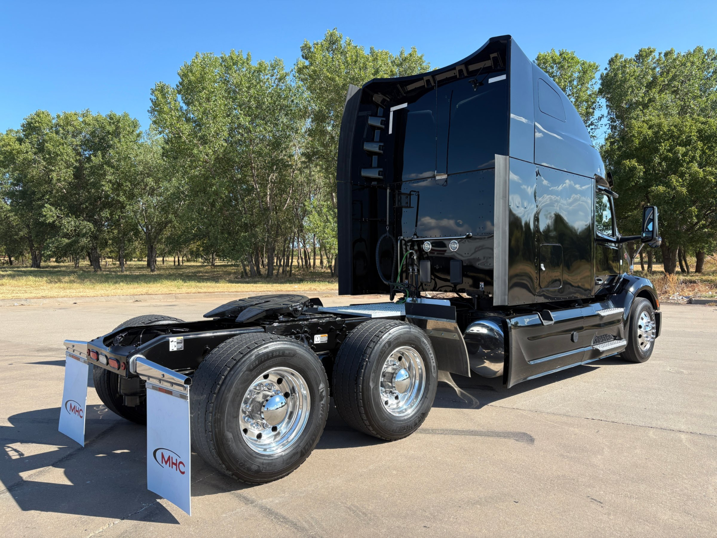 Peterbilt 579 tandem tractor with glossy black cab, rear wheels visible, no trailer attached, in a parking lot.