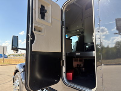 Peterbilt 579 cab door open showing interior sleeper area and steps, side mirror, and entry portal.