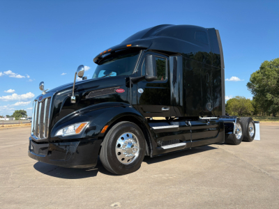 Peterbilt 579 conventional sleeper truck in black, side view showing chrome wheels and large sleeper cab.