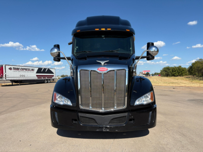 Peterbilt 579 truck front view showing chrome grille, headlights, and emblem in a parking lot.