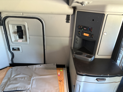 Interior of a Peterbilt truck cabin with control panel and storage, showing a doorway and side console.