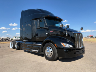 Peterbilt 579 tractor-trailer in black, side view, with sleeper cab and chrome wheels.
