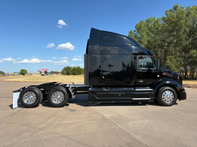 Peterbilt 579 tractor-trailer in-service side view showing black cab and tandem rear axles.