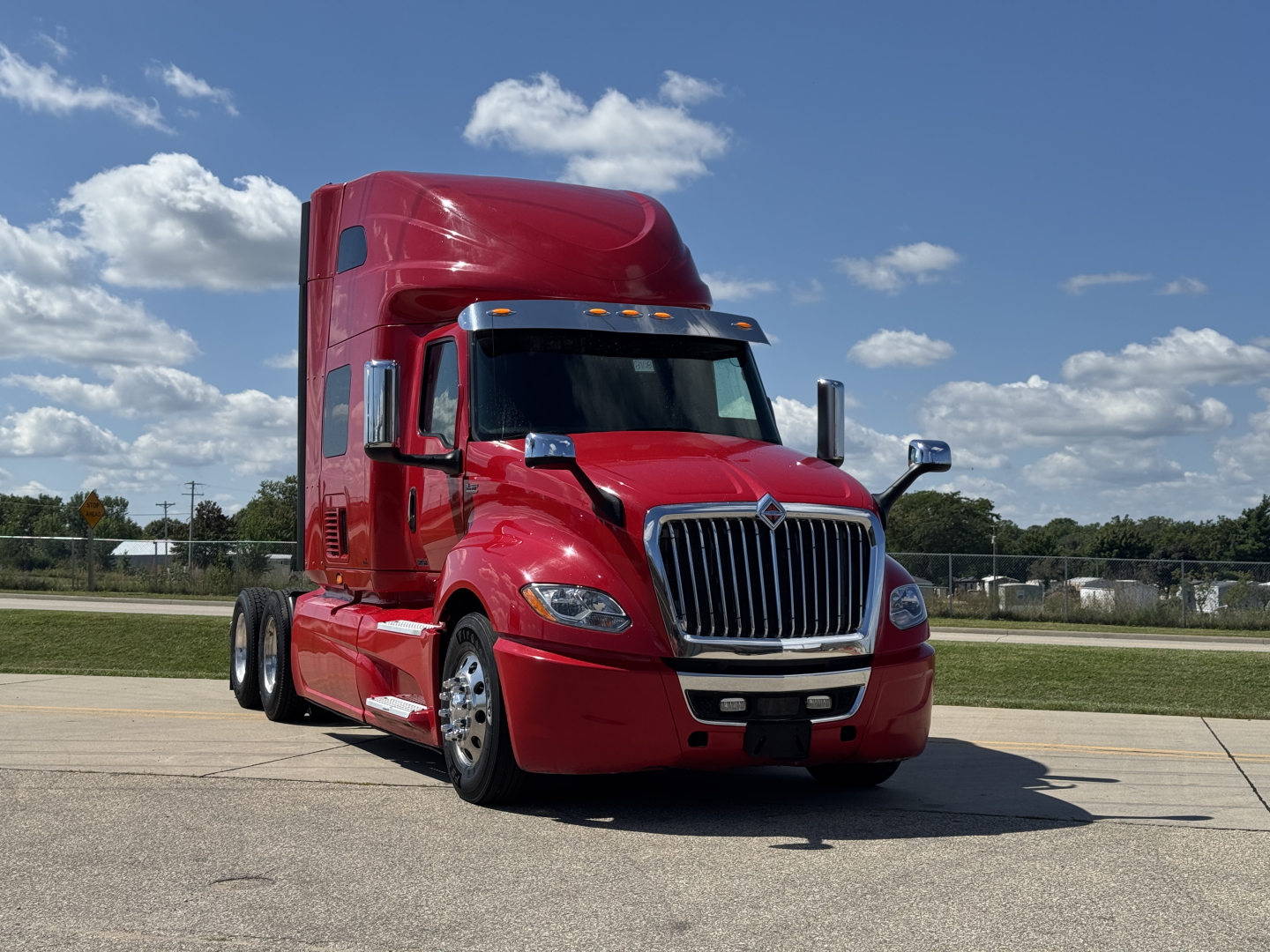 Red 2019 International LT625 sleeper truck with chrome grille and high cab, front view, highway setting.