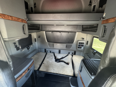 Truck sleeper cab rear interior with storage compartments, seat mounts, and cargo area showing flat floor with straps.