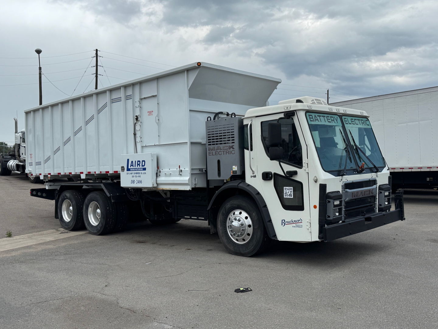Mack LR64 BE dump truck in serviceable condition showing dump bed and front cab with electric/digital components in a showroom lot.