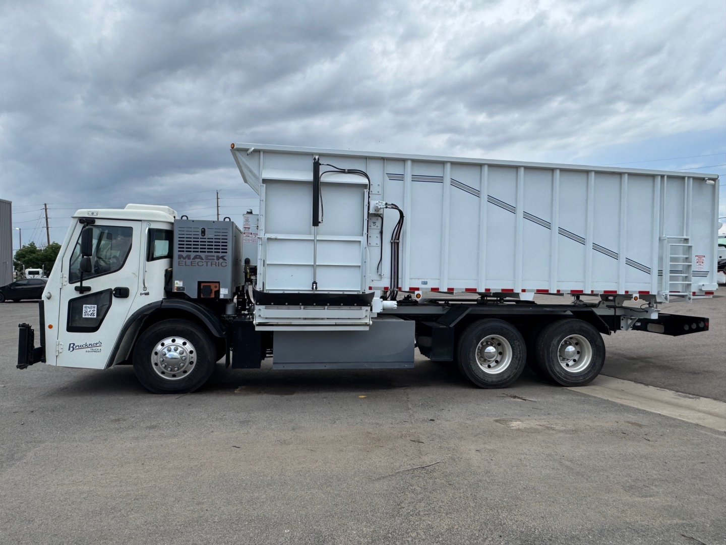 Mack LR64 BE dump truck side view showing cab, dual rear axles, dump bed, and fuel/fluid access panels.