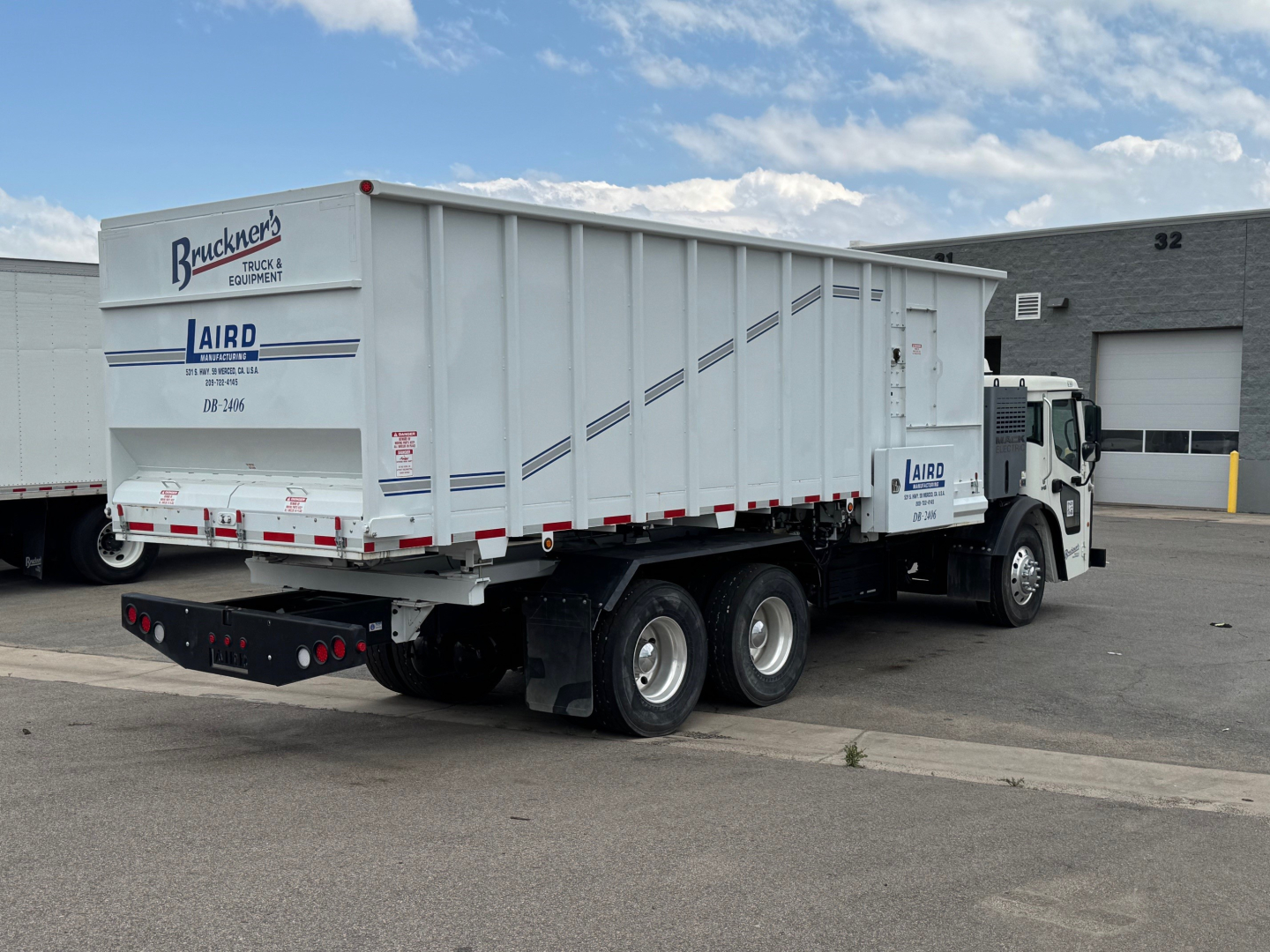 Truck tractor with dump trailer showing side and rear, Mack LR64 BE with Bruecker’s Truck & Equipment branding and AIRD logo on trailer