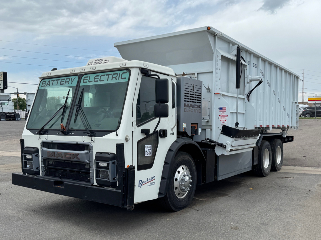 Mack LR64 BE truck in a dump body configuration, side view showing front cab and dumping cargo bed